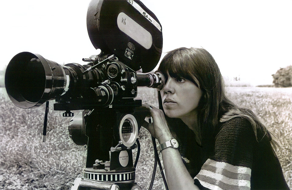 Regisseurin May Spils in jungen Jahren schaut durch eine analoge Filmkamera im Freien neben einer Sommerwiese