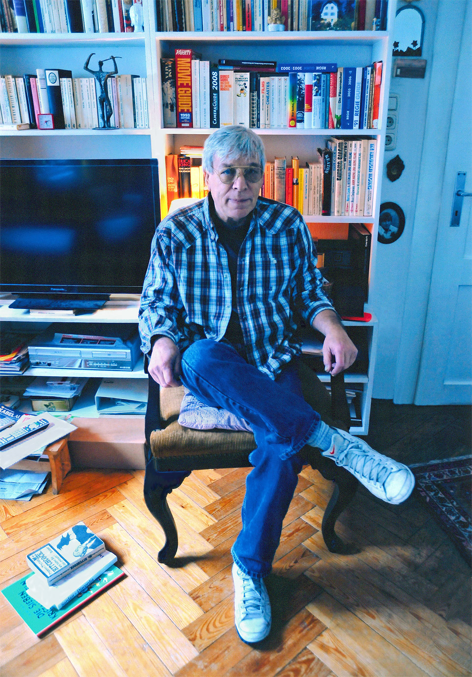 Werner Enke (älter) im Wohnzimmer in München-Schwabing auf einem Sessel sitzend vor einem Bücherregal